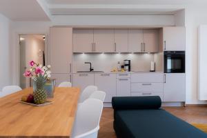 贝希特斯加登Alpine Apartements Maximilian的厨房以及带木桌和白色橱柜的用餐室。