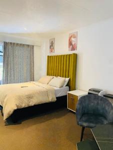 伯诺尼Linies guest house的一间卧室配有一张带黄床头板和椅子的床