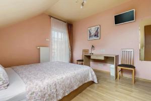 a bedroom with a bed and a desk and a television at Vila Liepa in Birštonas