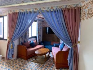 a living room with blue curtains and a couch at Diyafat Bladi in Oujda