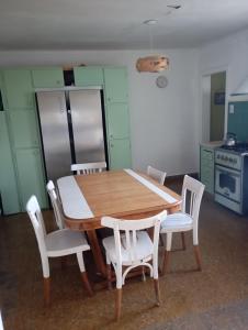 eine Küche mit einem Holztisch und weißen Stühlen in der Unterkunft Casa para disfrutar en Necochea 5 personas in Necochea