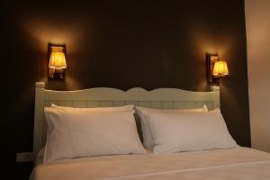 艾瓦勒克Defne Pansiyon Ayvalık的一张带白色枕头的床和墙上的两盏灯