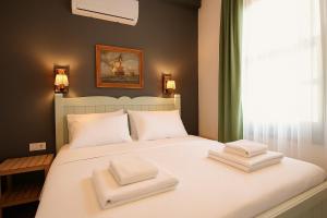 艾瓦勒克Defne Pansiyon Ayvalık的卧室里有一张床，床上放着两条毛巾。