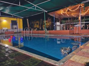 a swimming pool at night with lights on at Patil villa in Nagaon