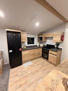 a kitchen with a black refrigerator and wooden cabinets at St Marys View in Whitley Bay +7 photos