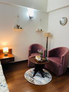 a living room with two chairs and a coffee table at Bs BnB Luxury Studio Apartment in Dehradun