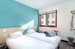 twee bedden in een kamer met een raam bij ibis budget Perpignan Centre Rénové en 2025 - Hôtel Economique au Centre ville de Perpignan in Perpignan