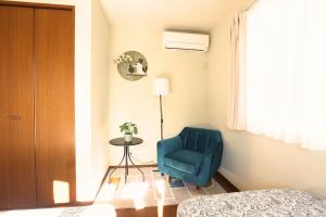 a bedroom with a blue chair and a table at 庭音日和 2つの半露天壺湯でくつろぐ宿 大家族向け広々一棟貸し 駐車場2台 浴室2箇所 in Omihachiman