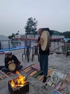 达兰萨拉DharteHouse Villa for Conscious Living and Events的一个男人抱着鼓站在火堆旁。