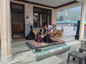 达兰萨拉DharteHouse Villa for Conscious Living and Events的一位女子坐在地毯上，手里抱着一把吉他。