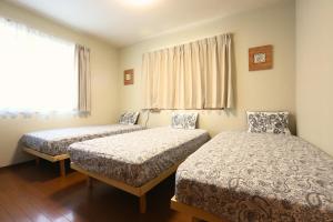 a bedroom with two beds and a window at 庭音日和 2つの半露天壺湯でくつろぐ宿 大家族向け広々一棟貸し 駐車場2台 浴室2箇所 in Omihachiman