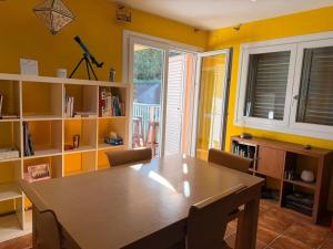 a dining room with a wooden table and yellow walls at Una casa ideal para familias o grupos de amigos in Caldes de Malavella