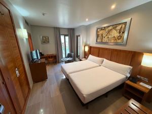 a hotel room with a white bed and a desk at Leflet Valme in Dos Hermanas