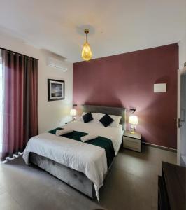 una camera da letto con un letto grande con una parete rossa di Seabreeze by Matteo a San Pawl il-Baħar