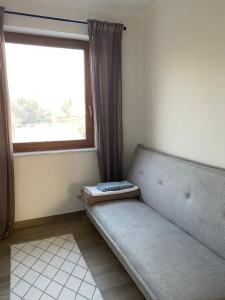 Un sofá sentado en una habitación con ventana. en Rybnicka 109A, en Skorka