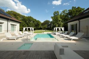 - une piscine avec des chaises longues blanches à côté d'une maison dans l'établissement Avalon Luxury Villa, à Miskolc