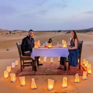 a man and woman sitting at a table in the desert at Tenere Luxury Camp in Merzouga