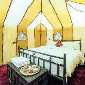 a bed in a tent with a plate of food on a table at Tenere Luxury Camp in Merzouga +5 photos
