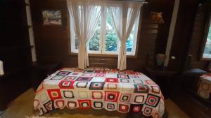 a bed with a quilt on it in front of a window at Apartamento Residencial Recanto Da Ferrugem in Garopaba