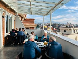 um grupo de pessoas sentadas à mesa numa varanda em Little Buddha Inn em Catmandu