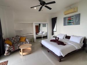 a bedroom with a bed and a couch and a ceiling fan at Mae Haad Sunset 2 in Koh Tao