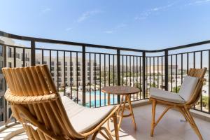due sedie e un tavolo su un balcone con vista di VayK - Chic 2BR in Town Square with Pool View a ‘Ūd al Bayḑāʼ