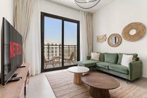 un soggiorno con un divano verde e una TV di VayK - Chic 2BR in Town Square with Pool View a ‘Ūd al Bayḑāʼ