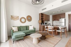 un soggiorno con un divano verde e una cucina di VayK - Chic 2BR in Town Square with Pool View a ‘Ūd al Bayḑāʼ