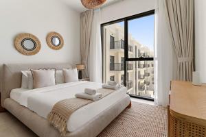 una camera da letto con un letto grande e una grande finestra di VayK - Chic 2BR in Town Square with Pool View a ‘Ūd al Bayḑāʼ Altre 13 foto