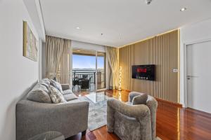 迪拜Burj View Luxury 1BR - Full Sea View Private Beach - Anantara Palm的有两把椅子和一台电视的客厅