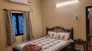 a bedroom with a bed and a window at Ferns Cottage in Calangute