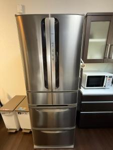 a stainless steel refrigerator in a kitchen next to a microwave at hibiki hotel osaka in Osaka