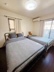 two beds in a room with two windows at hibiki hotel osaka in Osaka