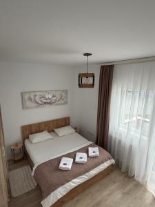 a bedroom with a bed with two towels on it at Malina Residence Aparthotel in Cisnădie