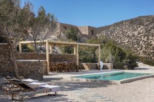 a pool with a table and chairs next to a building at New Project Fos in Platis Yialos Sifnos
