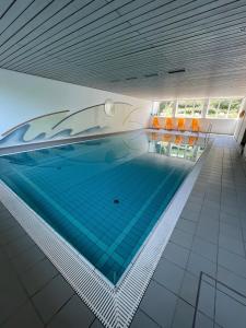 a swimming pool in a building with orange chairs at Ferienwohnung Alpenpanorama in Oberaudorf