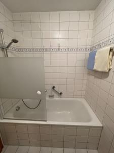 a white bath tub in a white tiled bathroom at Ferienwohnung Alpenpanorama in Oberaudorf +9 photos
