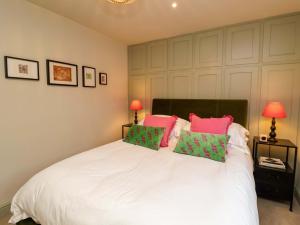 a bedroom with a white bed with pink and green pillows at Fairview in Saxmundham