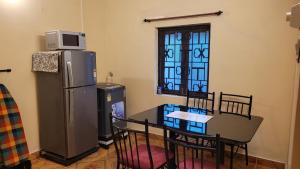 a kitchen with a table and a refrigerator and a window at Ferns Cottage in Calangute +16 photos