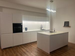 a white kitchen with white cabinets and a sink at Emmas Apartments in Duisburg