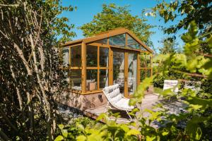 un gazebo con due sedie bianche in un giardino di Large Greenhouse op Boetiekpark de Kas a Scherpenzeel