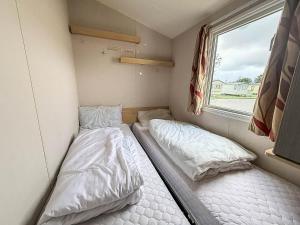 two beds in a small room with a window at Great 8 Berth Caravan For Hire At Seawick Holiday Park In Essex Ref 27227Sw in Clacton-on-Sea +16 photos
