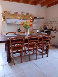 a kitchen with a table with chairs and a vase with flowers at Le chene vert in Saint-Front-de-Pradoux