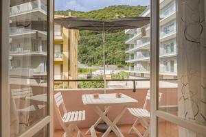 einen Balkon mit einem Sonnenschirm, einem Tisch und Stühlen in der Unterkunft Peace House - Relax a Due Passi dal Mare in Finale Ligure + 13 Fotos