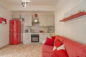 ein Wohnzimmer mit einem roten Sofa und einer Küche in der Unterkunft Peace House - Relax a Due Passi dal Mare in Finale Ligure