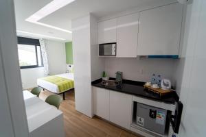 a kitchen with white cabinets and a bed in a room at GREEN STUDIO TARRAFAL - Ap 02 in Tarrafal