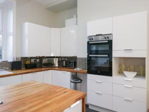 eine weiße Küche mit weißen Schränken und einem Holztisch in der Unterkunft Rocklands in Shap