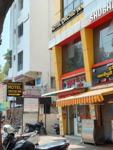 艾哈迈达巴德Hotel Orchid Inn的停在大楼前的一条有摩托车的街道