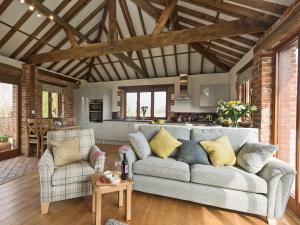 a living room with a couch and a kitchen at Elm Tree Barn in Felmingham