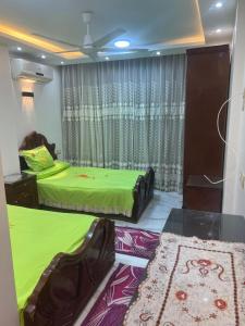two beds in a room with green sheets and a window at Aswan in Nag` el-Ramla